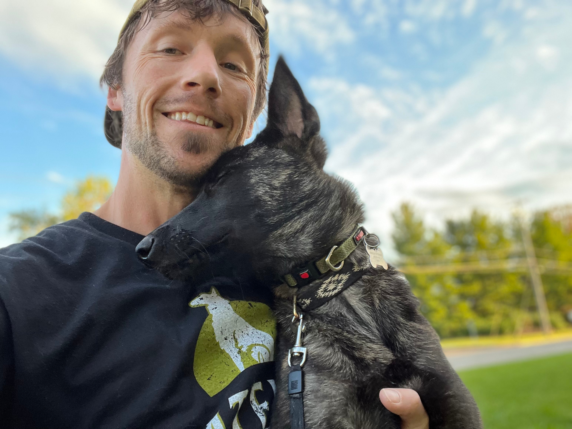 David Gumm embracing a calm trained dog at a park